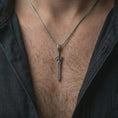 Load image into Gallery viewer, An oxidized fantasy sword pendant is worn on the neck in a close-up lifestyle shot, centered on the chest as a powerful warrior amulet.