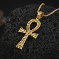 Load image into Gallery viewer, Gold plated ankh cross pendant necklace on textured volcanic rock, premium close-up studio composition emphasizing the sacred key of life form, hieroglyphic patterns, and ancient amulet design.