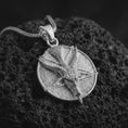 Load image into Gallery viewer, Polished silver goat pentagram pendant necklace on textured volcanic rock, centered macro jewelry photo with detailed horned goat relief and bright silver highlights.