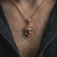Load image into Gallery viewer, Rose gold plated cracked skull pendant necklace worn on the chest, close-up lifestyle shot featuring the dark cracked skull design with warm rose gold tones.