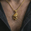 Load image into Gallery viewer, Gold plated cracked skull pendant necklace worn on the chest, premium lifestyle jewelry photo with the edgy skull pendant centered on a spiga chain.