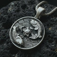 Load image into Gallery viewer, Oxidized koi fish lotus pendant necklace on textured volcanic rock, close-up studio shot highlighting the twin koi relief, lotus flower center, wave pattern, and antique silver contrast.