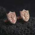 Load image into Gallery viewer, Rose gold plated Saint Michael cufflinks are photographed on porous volcanic rock in a close-up studio composition with refined luxury lighting and religious detail.