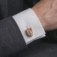 Load image into Gallery viewer, A rose gold plated Saint Michael cufflink is worn on a shirt cuff in a close-up lifestyle composition, highlighting its shield frame and Saint Michael design.
