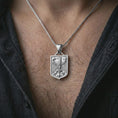 Load image into Gallery viewer, Polished silver German eagle shield pendant necklace worn on the chest, masculine lifestyle shot highlighting the bright silver finish, shield shape, and sculpted eagle relief.