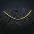 Load image into Gallery viewer, A gold plated foxtail chain necklace lies on textured volcanic rock in a dramatic studio macro shot, highlighting the 2.70mm woven chain structure.