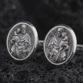 Load image into Gallery viewer, Oxidized Saint Joseph cufflinks displayed on dark volcanic rock in a macro studio photograph, featuring Saint Joseph holding the Christ Child with finely engraved Christian details.
