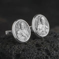 Load image into Gallery viewer, Polished silver Saint Francis cufflinks are displayed on black volcanic rock in a premium macro studio close-up with detailed Christian devotional artwork.