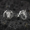 Load image into Gallery viewer, An oxidized bull head cufflink pair rests on dark volcanic rock in a macro studio close-up, showing a sculpted horned animal face inside octagon frames.