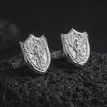 Load image into Gallery viewer, Polished silver Saint Michael cufflinks are displayed on black volcanic rock in a premium macro studio close-up with sharp shield edges and sacred warrior detail.