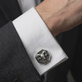 Load image into Gallery viewer, An oxidized ram skull cufflink is worn on a white shirt cuff in a close-up lifestyle shot, styled with a dark suit for a bold gothic formal look.
