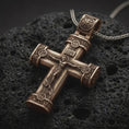 Load image into Gallery viewer, Bronze crucifix cross pendant necklace on textured volcanic rock, close-up studio shot highlighting the Jesus figure, INRI plaque, ornate barrel ends, and antique silver contrast.