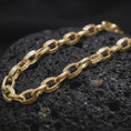 Load image into Gallery viewer, Gold plated Greek key chain necklace sits on textured volcanic rock in a dramatic studio macro shot, highlighting the repeating meander pattern.