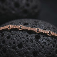 Load image into Gallery viewer, Rose gold plated Greek key chain necklace is photographed on porous volcanic rock in a close-up studio composition with refined patterned links.