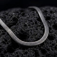 Load image into Gallery viewer, Oxidized sterling silver snake chain displayed on black volcanic rock, showing its smooth rounded profile and close flexible link structure.