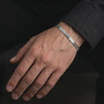 Load image into Gallery viewer, Polished sterling silver flat chain bracelet worn on the wrist, showing its smooth fit and refined herringbone pattern.