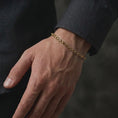 Load image into Gallery viewer, Gold plated slim box chain bracelet worn around a man’s wrist, displaying its compact rectangular link construction and refined masculine proportions in a premium close-up lifestyle shot.