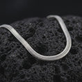Load image into Gallery viewer, Polished silver snake chain necklace on volcanic stone, highlighting the sleek continuous surface and clean reflective finish.