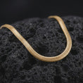 Load image into Gallery viewer, Gold plated snake chain arranged across black volcanic rock, emphasizing its smooth curved shape and minimalist chain design.