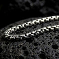 Load image into Gallery viewer, Oxidized sterling silver box chain displayed on black volcanic rock, showing its compact rectangular links and structured geometric profile.
