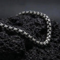 Load image into Gallery viewer, Oxidized sterling silver box chain bracelet displayed on black volcanic rock, showing its slim rectangular links and aged silver texture.