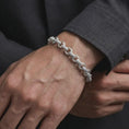 Load image into Gallery viewer, Polished silver decorative link bracelet worn by a male model, styled as a distinctive yet balanced everyday wrist accessory.