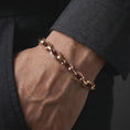 Load image into Gallery viewer, Rose gold plated Greek meander bracelet worn on a man’s wrist with formal dark clothing, displaying the decorative circular links in an elegant masculine close-up.
