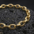 Load image into Gallery viewer, Gold plated Greek key bracelet resting on rugged volcanic rock, with detailed eternity motifs engraved around each circular link in a luxury macro studio close-up.
