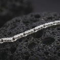 Load image into Gallery viewer, The polished silver Greek meander bracelet is arranged on textured black volcanic rock, highlighting its double-ended bar links and smooth circular connectors in a premium macro photograph.