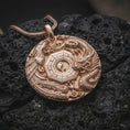 Load image into Gallery viewer, The rose gold plated Feng Shui pendant is arranged on black volcanic rock, emphasizing the intertwined dragon and phoenix, octagonal balance symbol, and richly sculpted circular medallion in a refined studio image.