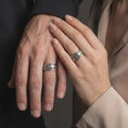 Load image into Gallery viewer, An oxidized dolphin ring is worn on a man’s and woman’s fingers, displaying the dark recessed ocean waves and raised marine motif in a close-up couple lifestyle shot.