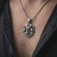 Load image into Gallery viewer, A samurai warrior pendant with an oxidized finish is worn on a man’s neck, displaying the dark recessed armor details, fierce masked expression, and circular sterling silver frame in a masculine lifestyle close-up.