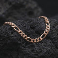 Load image into Gallery viewer, The rose gold plated 7mm Figaro chain necklace rests on black volcanic rock, emphasizing its articulated Italian link construction and bold masculine profile in a detailed macro image.