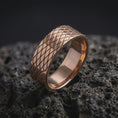 Load image into Gallery viewer, The rose gold plated lattice band is arranged on dark volcanic rock, emphasizing the symmetrical diamond texture, clean edges, and substantial geometric profile in a refined macro image.