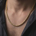 Load image into Gallery viewer, A gold plated 4mm round Byzantine chain necklace is worn on a man’s neck with dark clothing, highlighting the woven link texture and balanced statement profile in a refined close-up.