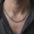 Load image into Gallery viewer, A 5mm Cuban chain necklace with an oxidized finish is worn on a man’s neck, displaying dark recessed link details and a clean masculine silhouette in a close-up lifestyle shot.