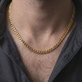 Load image into Gallery viewer, A gold plated 5mm Cuban chain necklace is worn on a man’s neck with dark clothing, highlighting the polished curb link texture and refined statement appeal in a masculine close-up.