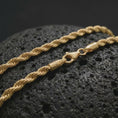 Load image into Gallery viewer, A gold plated 3mm rope chain necklace lies across rugged volcanic rock, featuring a compact twisted link structure and subtle masculine shine in a luxury macro studio close-up.