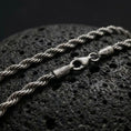 Load image into Gallery viewer, A 3mm rope chain necklace with an oxidized finish rests on dark volcanic rock, showing its tightly twisted sterling silver links and classic spiral texture in a macro studio close-up.
