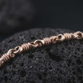 Load image into Gallery viewer, The rose gold plated barrel link chain necklace is arranged on black volcanic rock, emphasizing its ribbed cylinder details, flexible structure, and dimensional link pattern in a refined macro image.