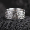 Load image into Gallery viewer, The polished silver Elven fantasy ring is displayed on textured black volcanic rock, highlighting the raised star motif, elegant interlace pattern, smooth edges, and wide sterling silver band in a premium macro photograph.