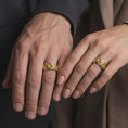 Load image into Gallery viewer, A gold plated gothic skull snake ring is worn on a finger, highlighting the raised serpent, memento mori skull imagery, sculpted roses, and distinctive alternative wedding band style in a refined close-up lifestyle shot.