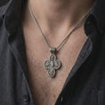 Load image into Gallery viewer, An oxidized sterling silver Saint Michael cross pendant is worn on the neck, displaying the double sided Christian design, protective symbolism, and detailed sculptural cross form in a close-up lifestyle photograph.