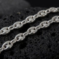 Load image into Gallery viewer, The polished silver 11mm Mariner chain necklace is displayed on textured black volcanic rock, highlighting the smooth puffed anchor links, reflective sterling silver surfaces, and bold wide-link construction in a premium macro photograph.