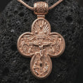 Load image into Gallery viewer, The rose gold plated archangel cross necklace is arranged on black volcanic rock, emphasizing the dimensional religious relief, decorative bail, and meaningful protection-inspired pendant design in a refined macro image.