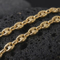 Load image into Gallery viewer, A gold plated 11mm Mariner chain necklace rests on rugged volcanic rock, showcasing the classic anchor link pattern, rounded puffed links, and substantial men's statement chain design in a luxury macro studio close-up.