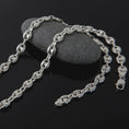 Load image into Gallery viewer, The polished silver 11mm Mariner chain necklace is displayed on textured black volcanic rock, highlighting the smooth puffed anchor links, reflective sterling silver surfaces, and bold wide-link construction in a premium macro photograph.