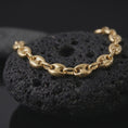 Load image into Gallery viewer, A gold plated 11mm Mariner chain bracelet rests on rugged volcanic rock, showcasing broad oval links, distinctive center bars, and a substantial nautical-inspired bracelet design in a luxury macro studio close-up.