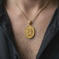 Load image into Gallery viewer, A gold plated St. Christopher travelers medal is worn on the chest, highlighting the saint carrying the Christ Child, symbolic wave details, and meaningful Catholic protection necklace design in a refined lifestyle shot.