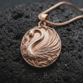 Load image into Gallery viewer, The rose gold plated swan necklace is arranged on black volcanic rock, emphasizing the elegant curved neck, detailed feather relief, decorative water motifs, and refined symbolic bird pendant design.